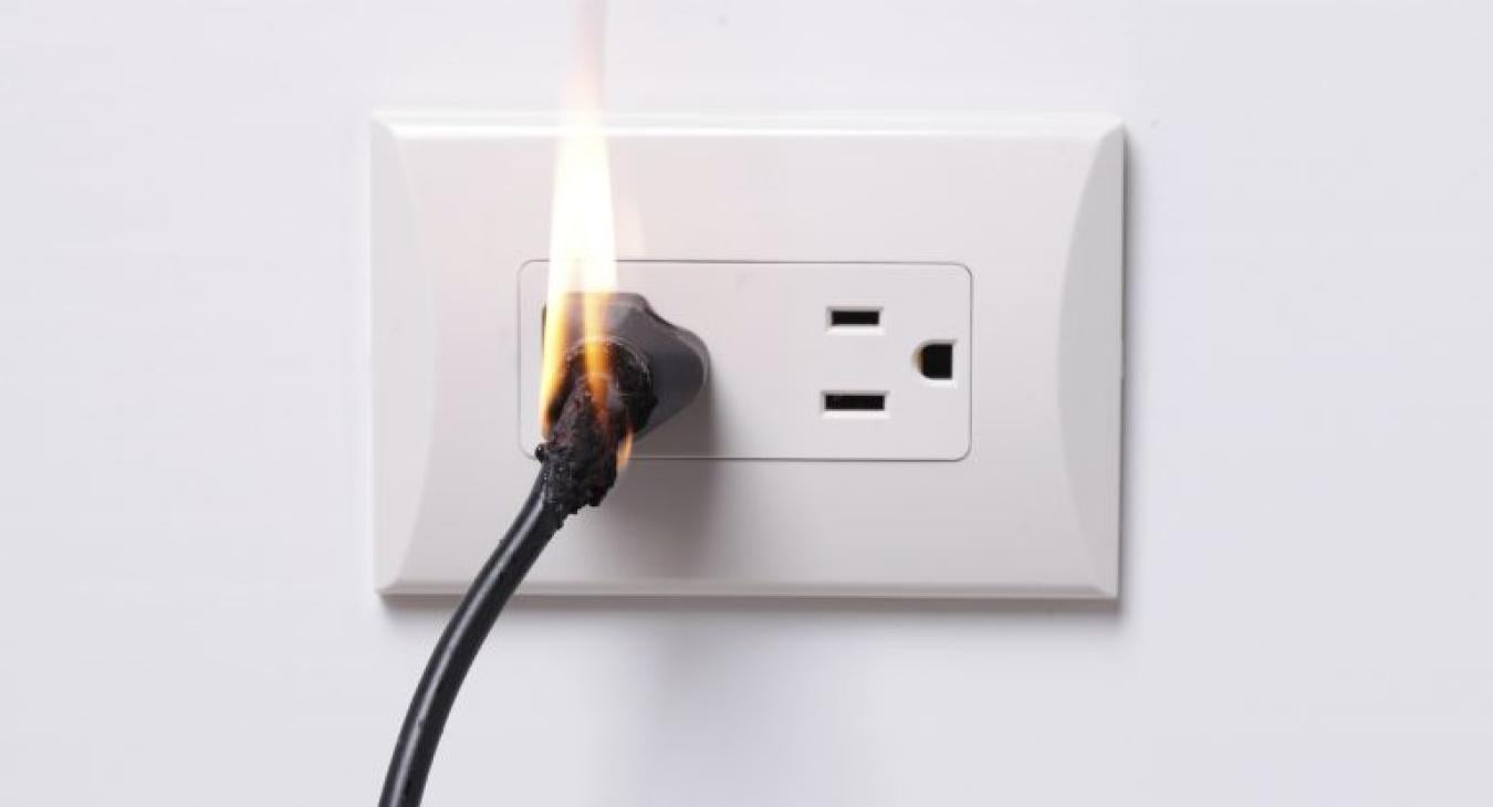 photo of outlet with cord on fire
